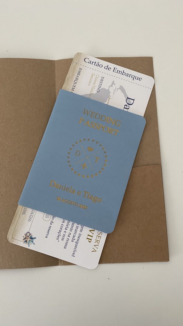 Convite de casamento viagem original em formato passaporte azul suave e bilhete de embarque detalhado, apresentados num envelope kraft rústico, Catia Silva Atelier